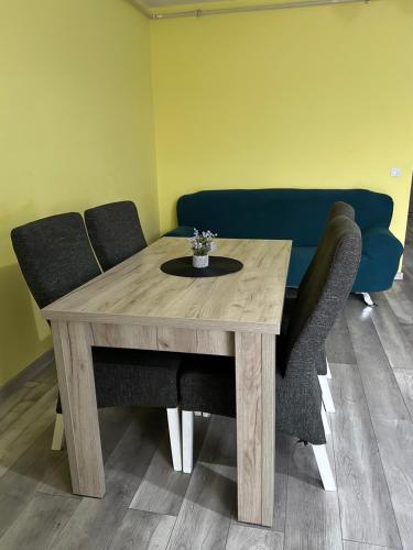 a wooden table with two chairs and a blue couch at Kiwi apartment in Bistriţa