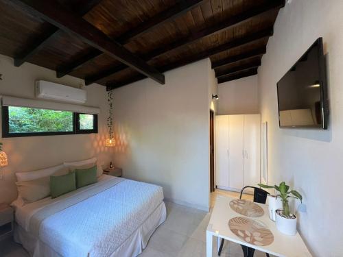 1 dormitorio con 1 cama blanca y TV en Depto Estudio p/ 2 personas. A estrenar! en Miramar