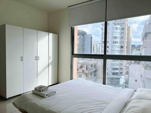 a bedroom with a large bed with a large window at Modern 3BR Apt next to Hotel Dieu in Beirut