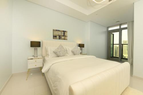 a white bedroom with a large bed and a window at Skyline Serenity 2BR Haven in Dubai