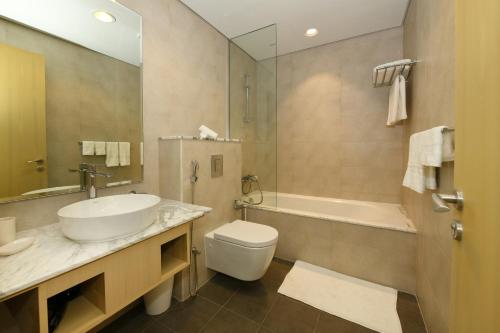 a bathroom with a sink and a toilet and a tub at Skyline Serenity 2BR Haven in Dubai