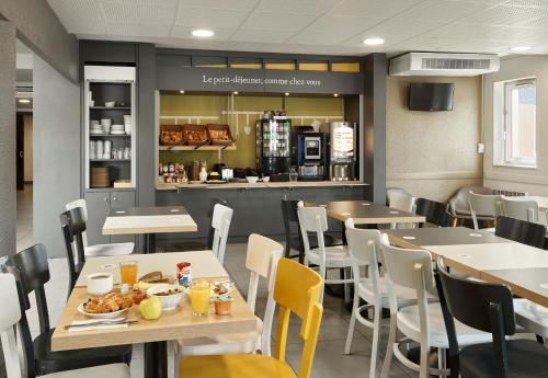 a restaurant with tables and chairs and a counter at B&B HOTEL Paris Nord Villepinte in Villepinte