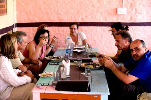 Eine Gruppe von Menschen, die an einem Tisch sitzen und Essen essen. in der Unterkunft Kings Retreat Jodhpur in Jodhpur