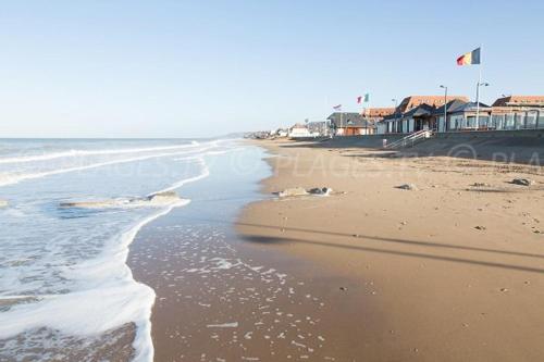 une plage de sable avec des maisons et l'océan dans l'établissement Appartement 50 m de la mer proche Deauville, à Villers-sur-Mer