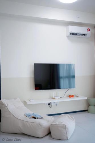 a living room with a tv and a white couch at Urban Suites Homestay by Vista Vibes in Jelutong