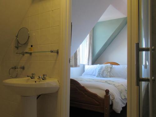 a bathroom with a sink next to a bed at Captain Howey Hotel in Kent