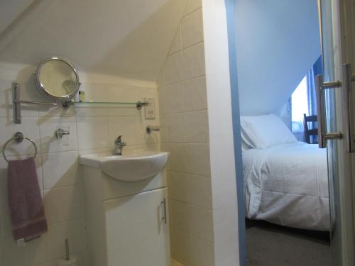 a bathroom with a sink and a mirror and a bed at Captain Howey Hotel in New Romney