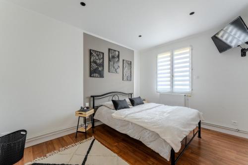 a white bedroom with a bed and a window at Le monde de Lucy in Annoeullin