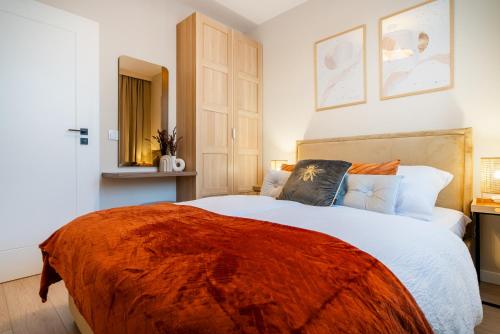 a bedroom with a large bed with an orange blanket at ApartamentySnu, Bulwary IV z parkingiem in Radom