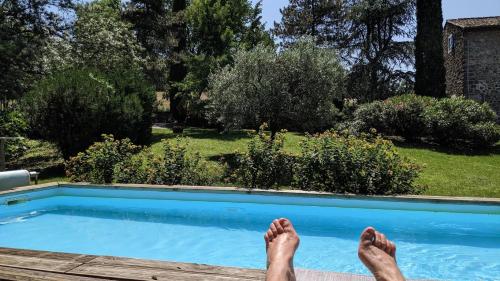 a person laying on a deck next to a swimming pool at Domaine Insolite du Petit Moras in Chomérac