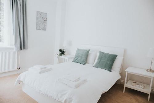 a white bedroom with a white bed with green pillows at A 3 bedroom apartment with parking in central Kingsbridge in Kingsbridge