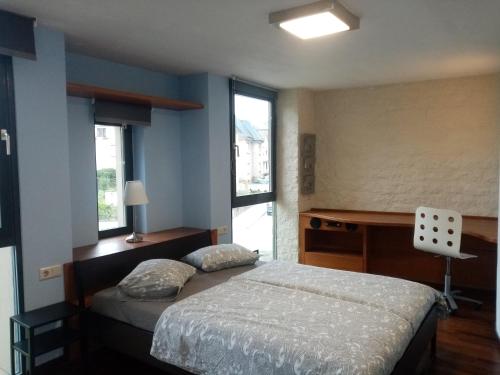 1 dormitorio con cama, escritorio y ventana en Wollefstuerm en Echternach