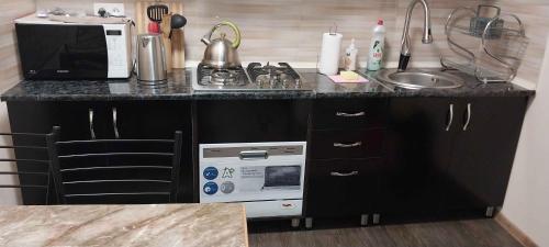 un comptoir de cuisine avec un évier et un micro-ondes dans l'établissement Full house, à Tbilissi