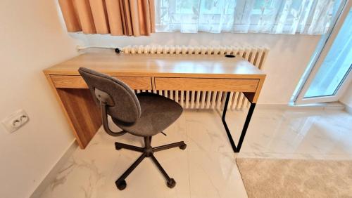 a desk with a chair next to a window at Apartman Laki in Tošin Bunar