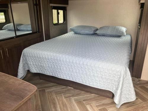 a bed with blue pillows on it in an rv at Cavendish Luxury Camping in Cavendish