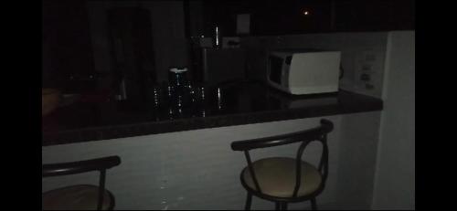 a kitchen counter with two chairs and a microwave at Heinz B. in Santa Ana de los Caballeros