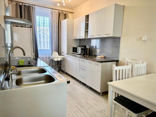 a kitchen with white cabinets and a sink and a table at Apartament Vistula Centrum 4 in Wisła
