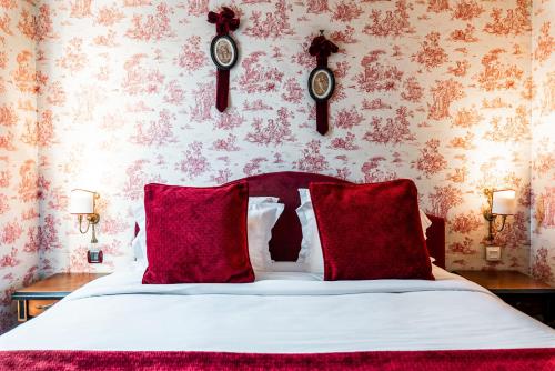 a bedroom with a bed with red pillows and clocks on the wall at Maison Eugenie in Paris