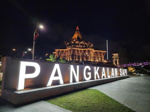 a sign in front of a large building at night at Riverbank Suites Kuching Waterfront in Kuching