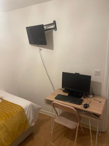 a desk with a computer and a lamp next to a bed at Angels Pad in Dagenham
