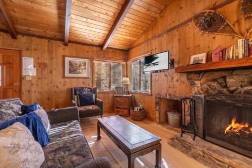 a living room with a fireplace in a log cabin at Donut Chalet with spa, BBQ grill, and firepit in Big Bear Lake