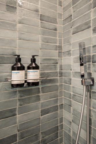 two bottles ofodorizers on a tiled bathroom wall at Agave Marina in Marciana Marina