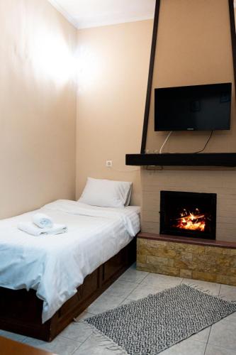 a bedroom with a bed with a fireplace and a flat screen tv at Toma's House in Makrinítsa