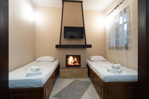 2 Betten in einem Zimmer mit Kamin in der Unterkunft Toma's House in Volos