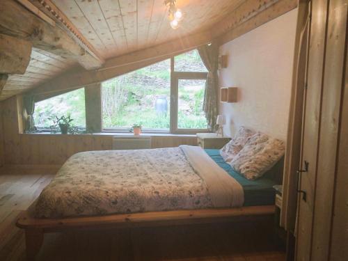 een bed in een kamer met een groot raam bij Charmant duplex 70m2,type châlet savoyard in Bourg-Saint-Maurice