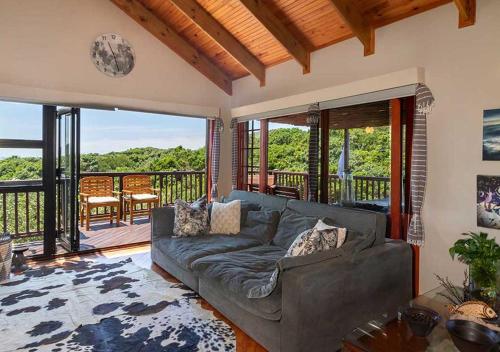 Una sala de estar con un sofá y un balcón. en Villa Mtati, en Port Alfred