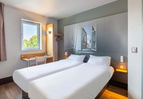 シャルトルにあるB&B HOTEL CHARTRES Le Coudrayのベッド2台と窓が備わるホテルルームです。