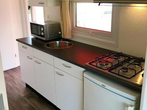 Il comprend une petite cuisine équipée d'une cuisinière et d'un évier. dans l'établissement Greenchalets Frejus Saint Aygulf, à Fréjus