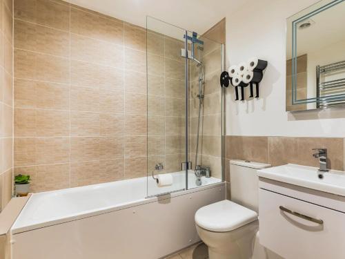 a bathroom with a tub and a toilet and a sink at 1 Bed in Brockenhurst 87525 in Brockenhurst