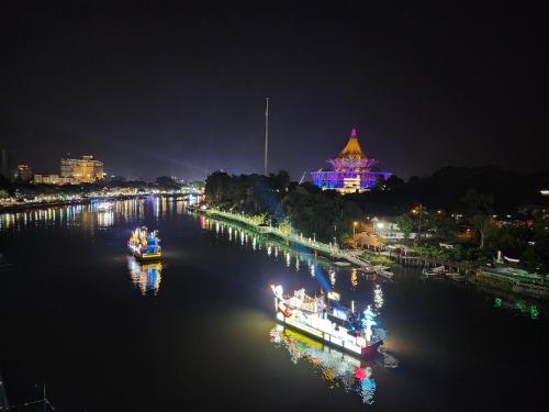 two boats in a river at night with a building at Riverbank Suites Kuching Waterfront in Kuching
