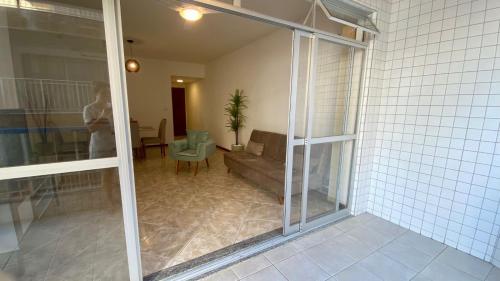 une personne debout dans un salon avec une porte coulissante en verre dans l'établissement Apartamento encantador a uma quadra do melhor trecho da Praia do forte- Cabo Frio, à Cabo Frio