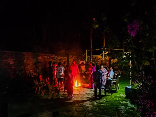 um grupo de pessoas em pé em torno de uma fogueira à noite em JMT Eco-Binsar by StayApart em Panuānaula
