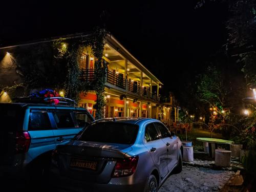 two cars parked in front of a house at night at JMT Eco-Binsar by StayApart in Panuānaula