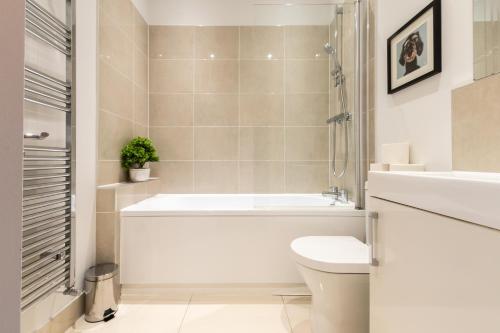 a bathroom with a tub and a toilet and a sink at Elegant 2 Bedroom Seymour Apartment by Smart Apartments in Southampton