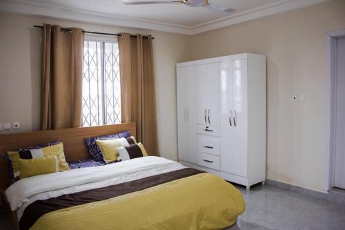 una camera con un grande letto e un armadietto bianco di KOJOSVILLA LUXURY APARTMENT a Tema
