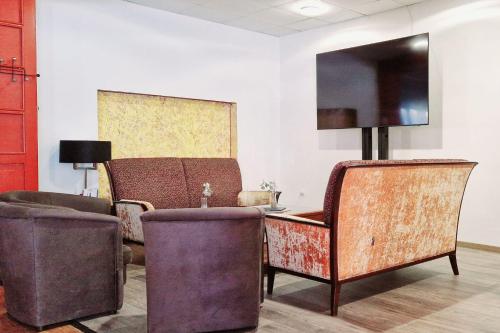 a room with two chairs and a table and a television at Hotel Eger & Park in Eger