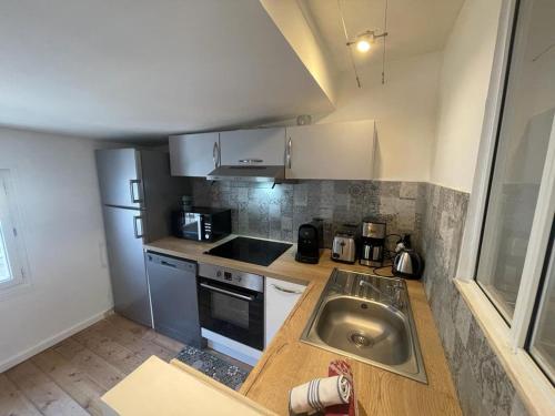 uma pequena cozinha com um lavatório e um fogão em L'escale Niortaise - Centre-ville - 10mn Gare - WIFI - Netflix em Niort