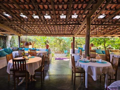 uma sala de jantar com mesas e cadeiras com toalhas de mesa brancas em Pousada Ilha Verde em Itacaré