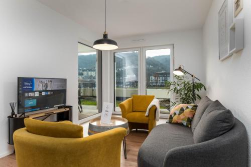 a living room with a couch and chairs and a tv at Vivamosel: Appartement mit Mosel & Burgblick - Balkon - Parken - Aufzug - Fahrradraum in Cochem