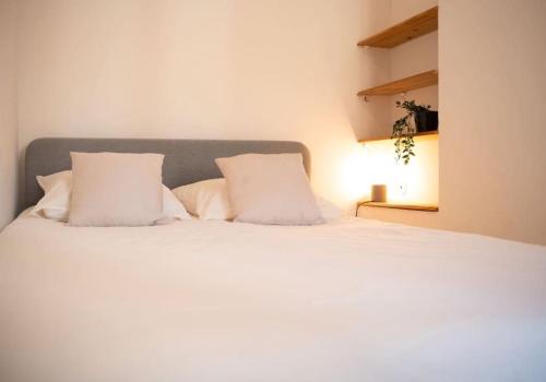 a bedroom with a white bed with two pillows at Maison au cœur de l’Estaque in Marseille