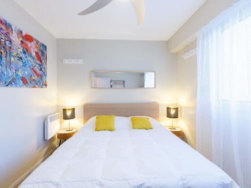 ein Schlafzimmer mit einem weißen Bett mit zwei gelben Kissen in der Unterkunft Apartment Les Ecureuils-1 by Interhome in Les Mathes