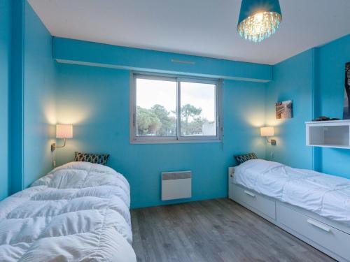 Cette chambre bleue comprend 2 lits et une fenêtre. dans l'établissement Apartment Les Ecureuils-1 by Interhome, aux Mathes