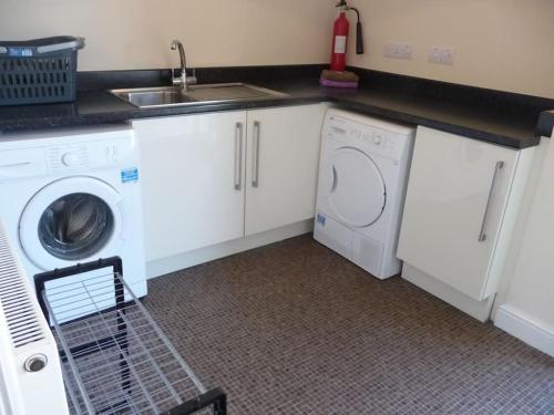 a kitchen with a washing machine and a sink at Otter House in Arle