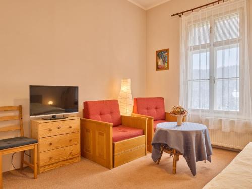 een woonkamer met een tv en 2 stoelen en een tafel bij Apartment Koreff-2 by Interhome in Janske Lazne