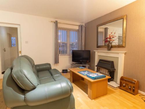 a living room with a leather couch and a television at Villa Heather Cottage by Interhome in Inverness