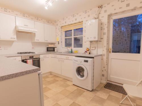 a kitchen with white cabinets and a washer and dryer at Villa Heather Cottage by Interhome in Inverness